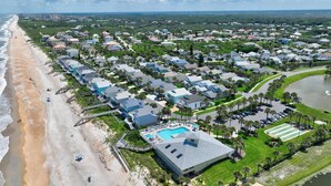 An aerial view of a coastal residential area with houses, a beach, and a swimming pool. - Sea Colony Monthly Retreat | Canal View | Steps to Private Beach & Pool | Dog Friendly (Palm Coast)