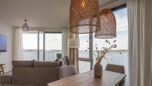 En moderne stue med sofa, spisebord og udsigt til vandet.