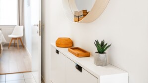 Ein modernes Badezimmer mit einem weißen Waschtisch, einem Holztablett, einer Topfpflanze und einem runden Spiegel.