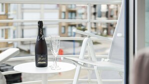Ein Balkon mit einer Flasche Freixenet Champagner und zwei Gläsern auf einem weißen Tisch.