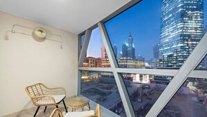Een hoog gelegen kamer met een groot raam met uitzicht op een stadsbeeld, inclusief een opvallende klokkentoren.