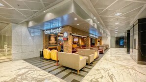 Een moderne lobby met een koffiebar, een zithoek en een receptiebalie.