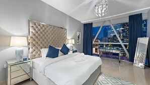 Een moderne hotelkamer met een groot bed, uitzicht op de stad en een bijzondere plafondlamp.