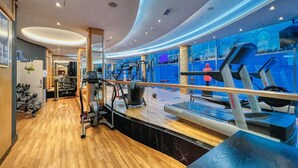 Een moderne fitnessruimte met cardioapparatuur, krachttoestellen en een houten vloer.