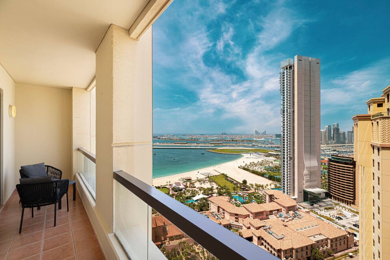 A balcony with a view of a beach, a tall building, and a cityscape.