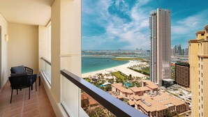 A balcony with a view of a beach, a tall building, and a cityscape. - World Class | 1BR | Breathtaking Beach Views (JBR, Dubai)