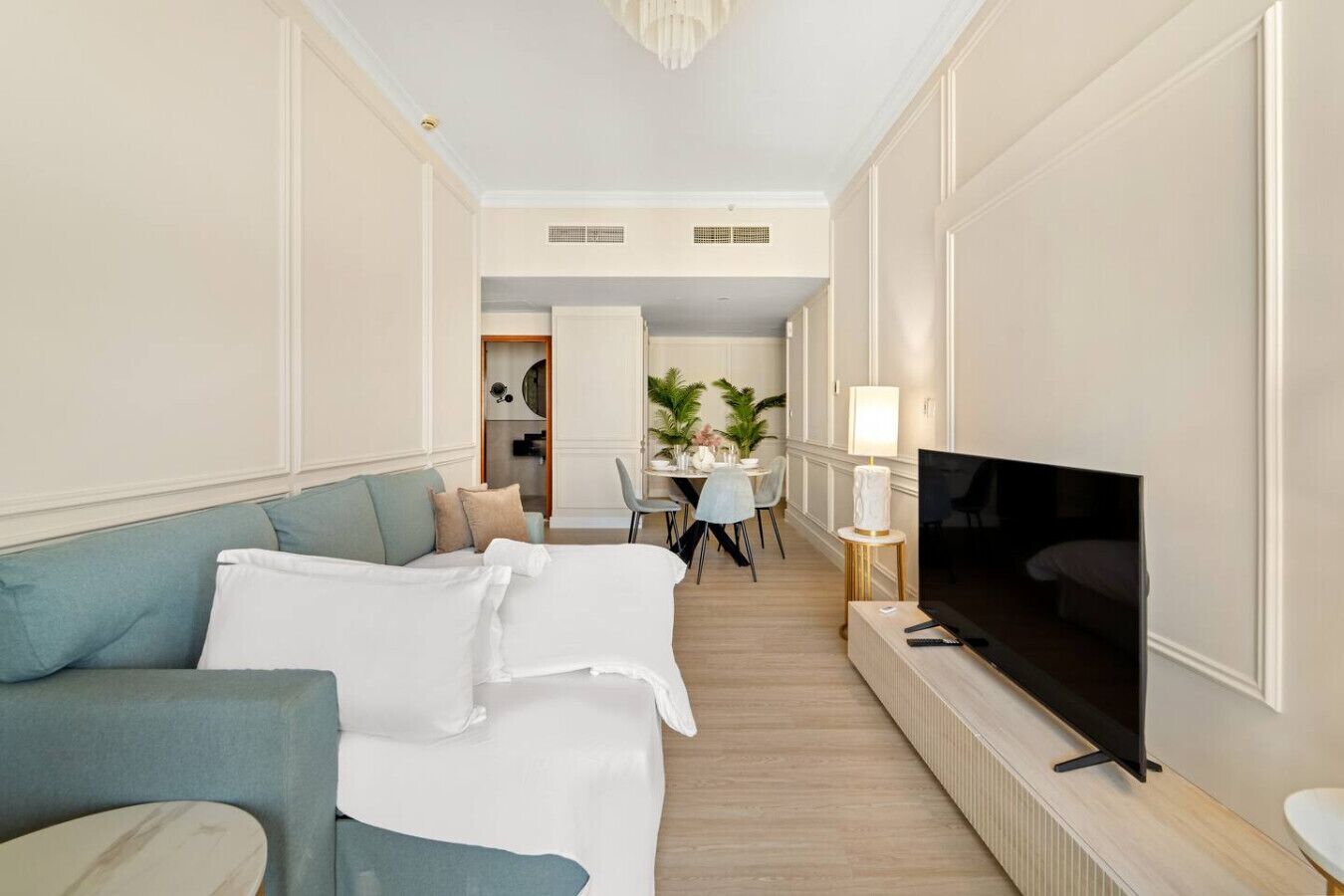 A hotel room with a sofa, a TV, and a dining area in the background.