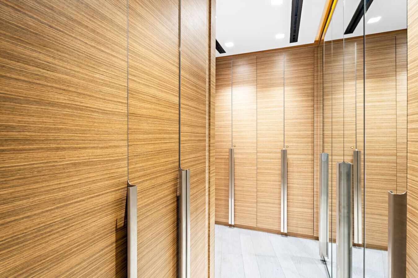 A modern elevator with wooden paneling and metallic handles.