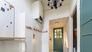 A hallway with a green door, white walls, a wooden shelf, and a radiator. - Amazing Holiday Home in Lauwersoog With Sauna (Lauwersoog)