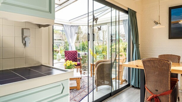 A kitchen with a large sliding glass door leading to an outdoor area with a dining table and chairs. - Amazing Holiday Home in Lauwersoog With Sauna (Lauwersoog)