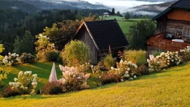Paesaggio rurale con una casetta di legno e una stalla.