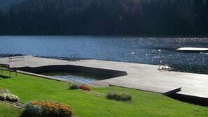 Una terrazza affacciata su un lago con un'area per nuotare, circondata da una foresta.