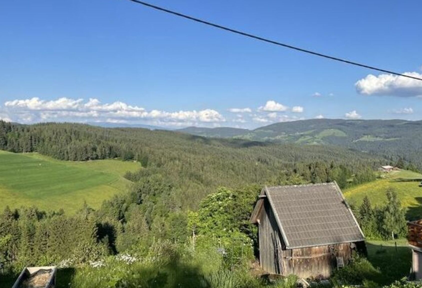 A rural landscape with a wooden cabin and a solar panel on the roof.