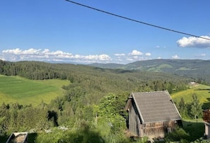 A rural landscape with a wooden cabin and a solar panel on the roof.