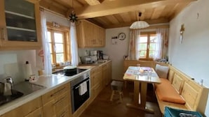Un'accogliente cucina in stile baita con mobili in legno, un tavolo da pranzo con una panca e un angolo cottura.