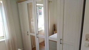 A bedroom with a bed, a wardrobe with glass doors, and a view of a balcony. - Fillner 2 Modern Retreat (Scharbeutz)