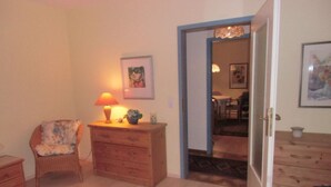 A bedroom with a bed, a chair, a dresser, and a door leading to another room. - Pellworm in Haus Halligblick (Dagebuell)