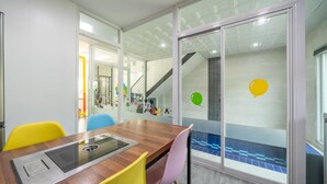 A modern meeting room with a glass partition, a wooden table, and colorful chairs. - Gapyeong Ttonggangaji Kids Poolvilla (Gapyeong)