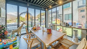 A dining area with a table, chairs, and a view of a cityscape through large windows.