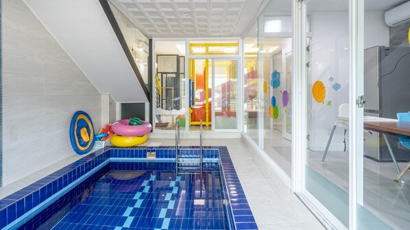 Relax by the pool with a view of the adjacent room, featuring a bathtub and a comfortable seating area.
