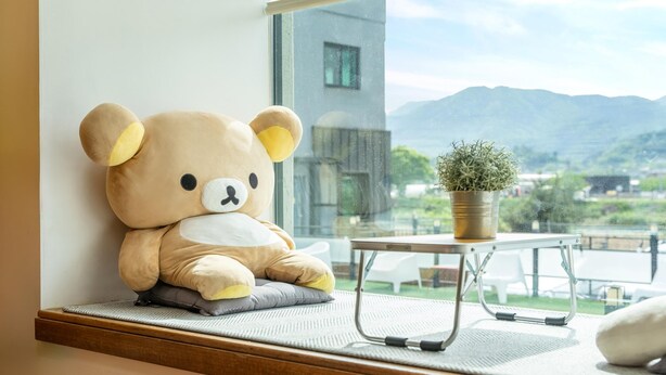 A large teddy bear sitting on a window sill next to a small table with a potted plant. - Gapyeong Ttonggangaji Kids Poolvilla (Gapyeong)