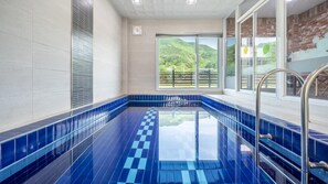 Relax by the pool with a serene view of the lush landscape through large windows.