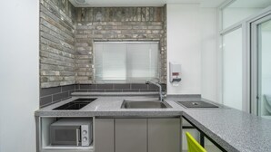 A modern kitchen with a built-in stove, a sink, and a window with blinds. - Gapyeong Ttonggangaji Kids Poolvilla (Gapyeong)