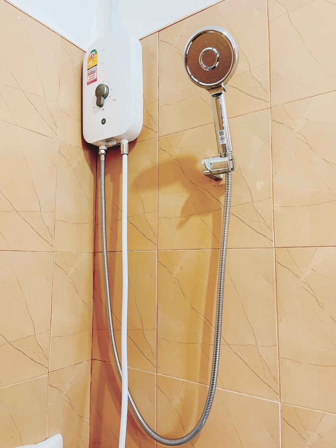 A shower with a handheld showerhead and a wall-mounted control panel.