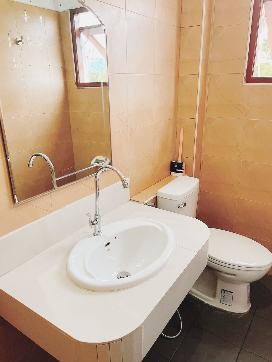 A bathroom with a white sink, a mirror, a toilet, and beige tiled walls.