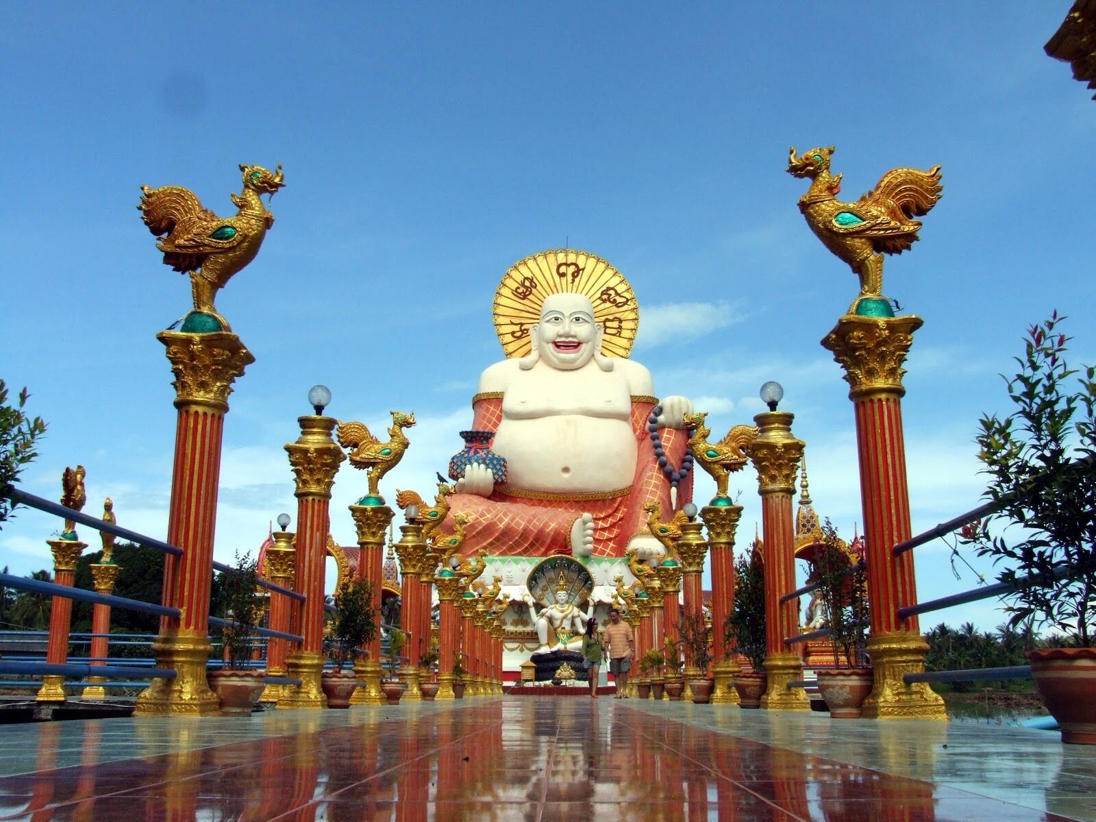 A large Buddha statue surrounded by golden columns and decorative elements.