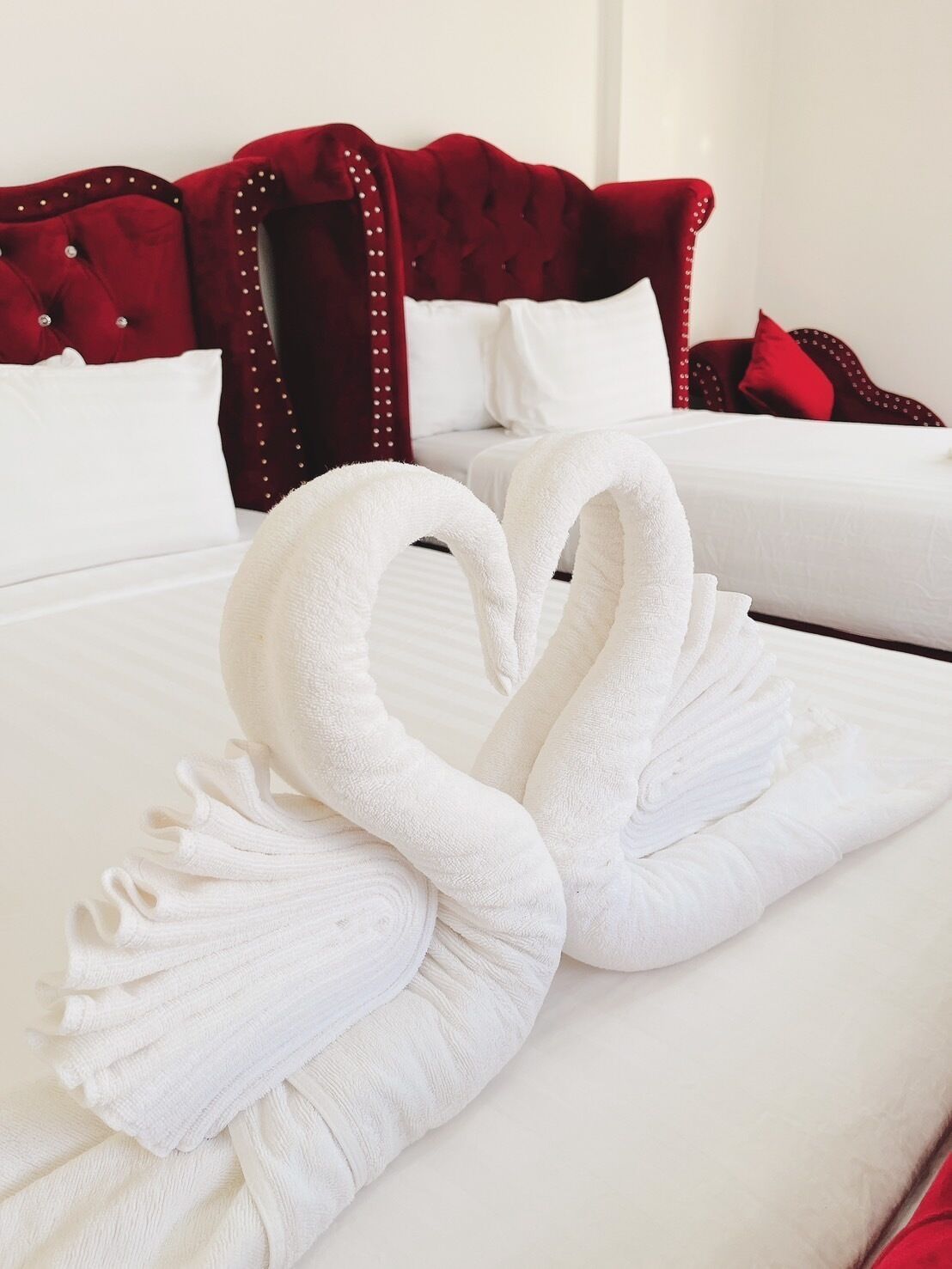 A hotel room with a bed featuring a decorative towel arrangement in the shape of two swans.