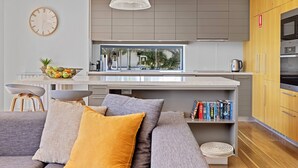 Una cocina moderna con un amplio ventanal, electrodomésticos integrados y una zona de estar acogedora con cojines.