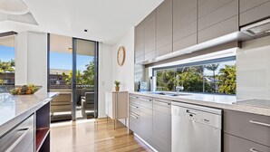 Una cocina moderna con un amplio ventanal, electrodomésticos de acero inoxidable y suelo de madera.
