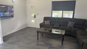 Een woonkamer met een donkergrijze bank, een bijpassende salontafel en een deur met een raam.