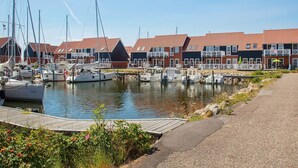 Un puerto deportivo con barcos amarrados, un muelle de madera y una hilera de casas con tejados rojos.