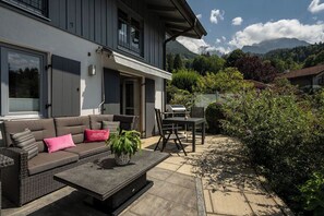 Ett modernt hus med en uteplats som har en soffa, ett bord och en grill.