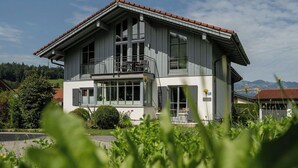 A two-story building with a balcony on the upper floor, large windows, and a red-tiled roof. - Ferienwohnung Marianne Bergpanorama (Berchtesgaden)