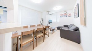 A modern living room with a sofa, a dining table with chairs, a TV, and artwork on the wall. - Tokyo Private House (tokyo)