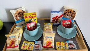 Un plateau contenant des articles pour le petit-déjeuner, notamment des biscuits, des céréales et du thé.