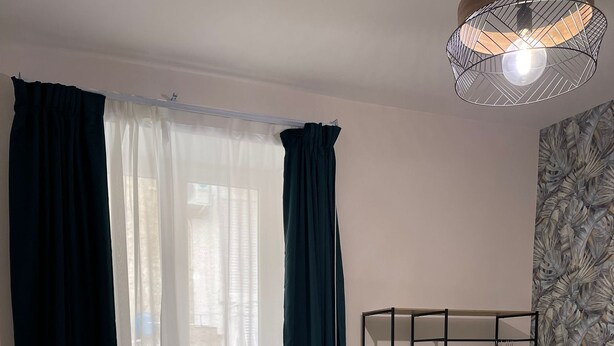 Une chambre à coucher avec un lit, une armoire et une fenêtre avec des rideaux.