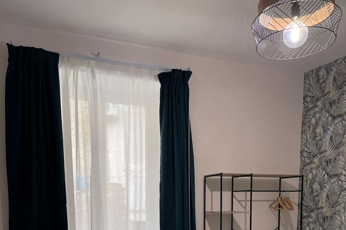 A bedroom with a bed, a wardrobe, and a window with curtains.