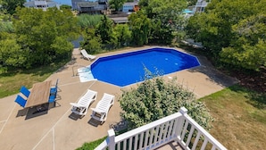 Ein Garten mit Swimmingpool, Liegestühlen und einer Holzterrasse.