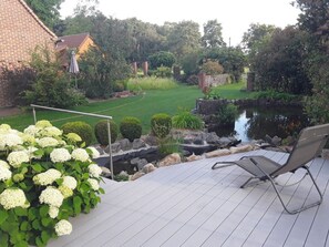 Une terrasse avec une chaise, un bassin et un jardin agrémenté d’hortensias blancs.