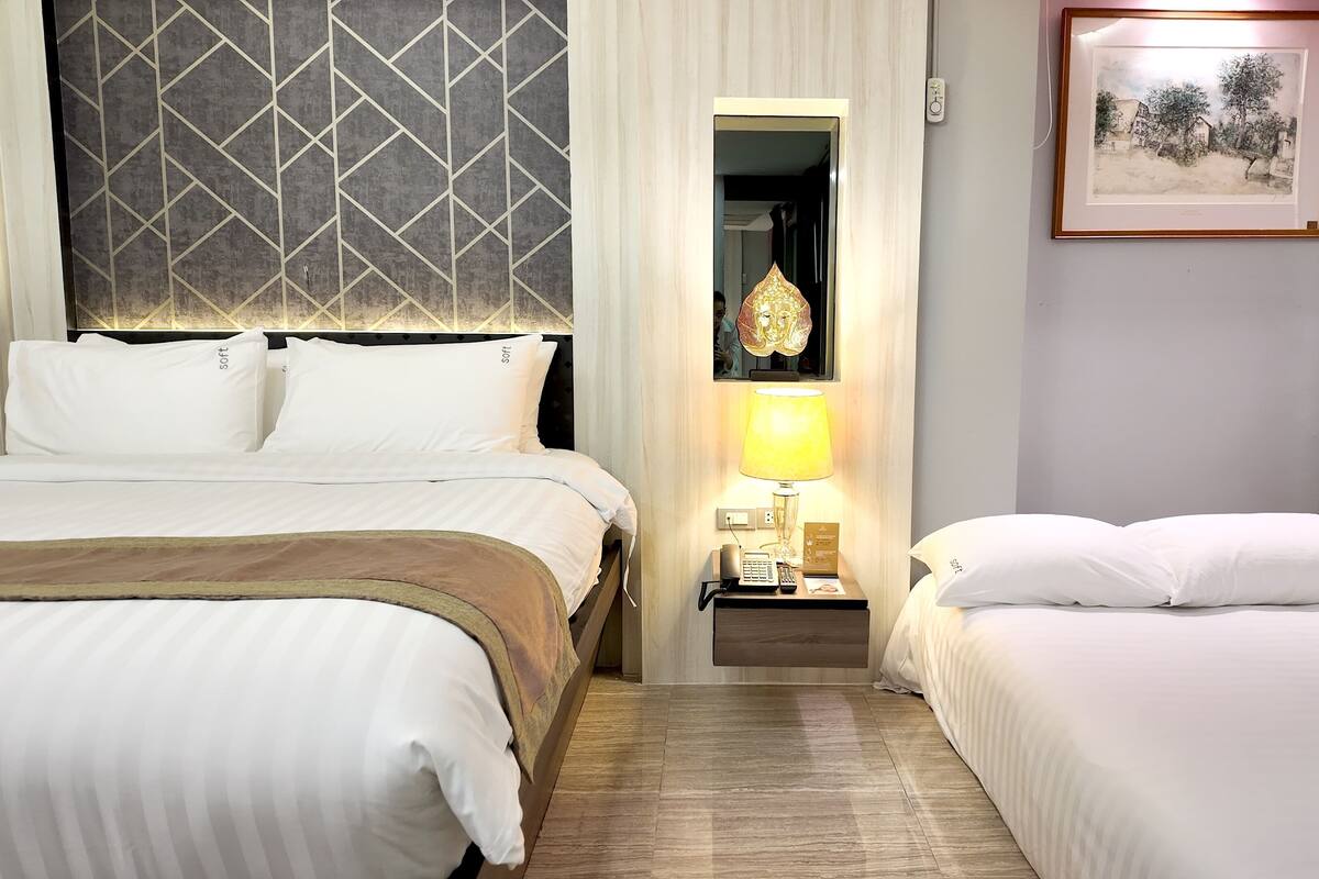 Een hotelkamer met een bed, nachtkastje, lamp en een lijst aan de muur.