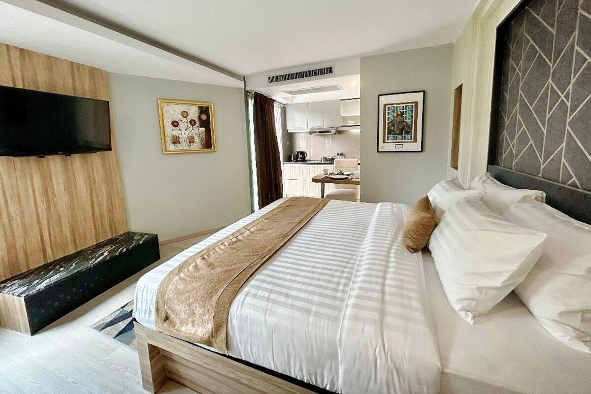 Een hotelkamer met een bed, een televisie, een bureau en een kitchenette.