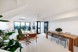 A modern interior with a dining area, a sofa, and a large window.