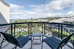 A balcony with two chairs and a table, overlooking a residential area with houses and greenery. - Pooch Friendly Sunrise Beach 3BR w/ Views (Noosa)