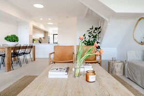 A modern living room with a wooden coffee table, books, a candle, and a vase with flowers. - Pooch Friendly Sunrise Beach 3BR w/ Views (Noosa)