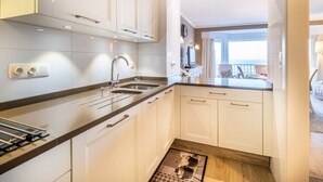 A modern kitchen with white cabinets, a double sink, and a wooden countertop. - Apartment in Ostend With Stunning Sea View (Koksijde)