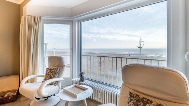 A balcony with a view of the beach, two white chairs, a small table, and a radiator. - Apartment in Ostend With Stunning Sea View (Koksijde)